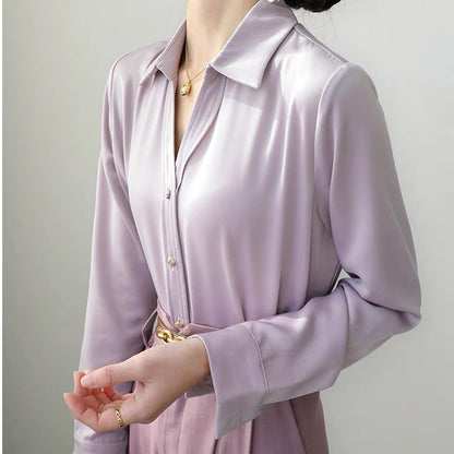 Elegante Frau in lila Satinbluse mit goldenen Knöpfen und Gürtel, modisches Outfit, stilvolle Damenmode, luxuriöser Stoff, Bürolook.