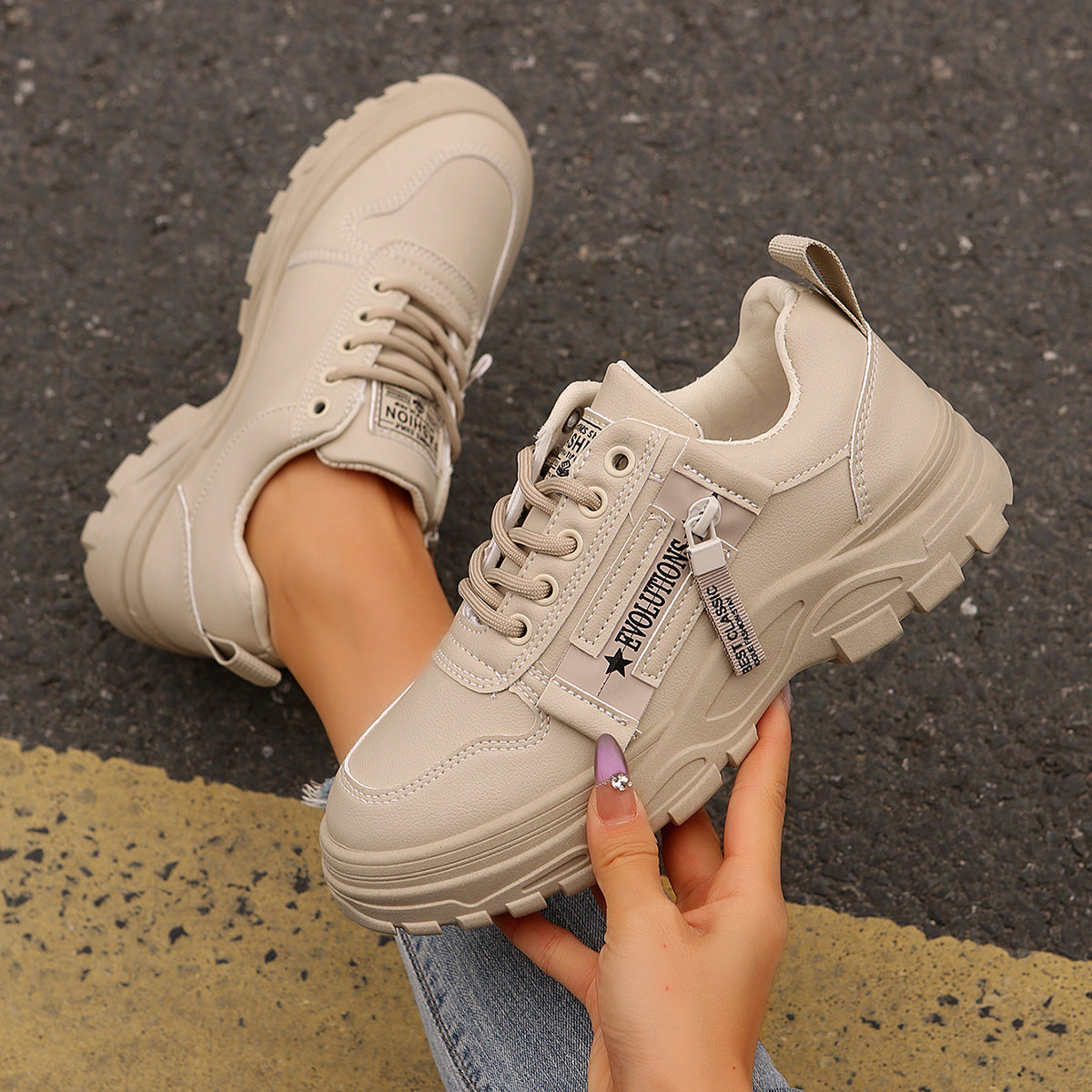 Beige Sneaker mit dicker Sohle auf Asphalt, modisch und robust, ideal für Damen. Trendige Straßenschuhe, perfekt für urbanen Stil und Komfort.