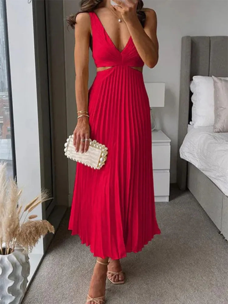 Frau in rotem, plissiertem Kleid mit V-Ausschnitt, hält eine weiße Clutch. Steht in modernem Schlafzimmer mit Bett und Fenster. Elegante Abendmode.