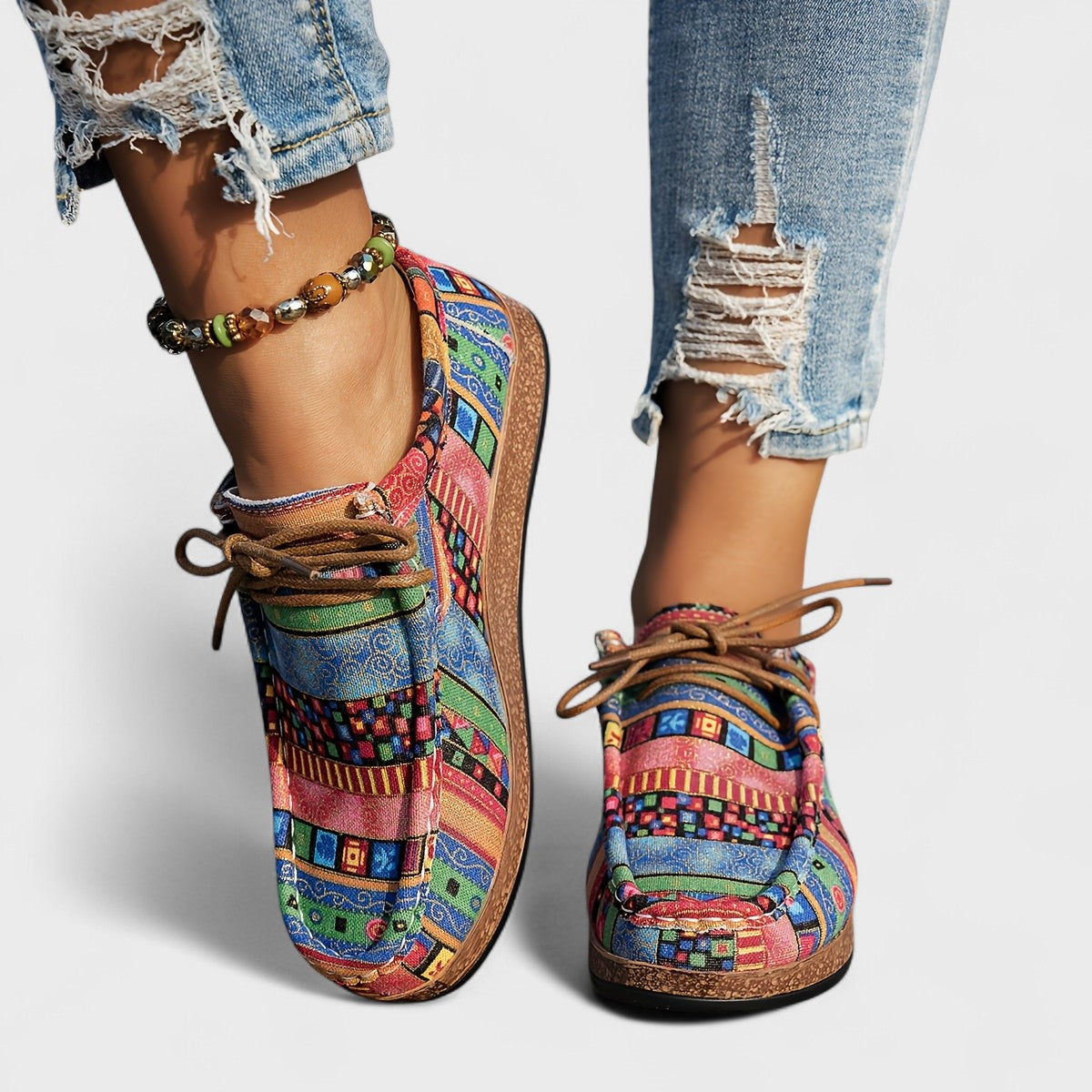 Bunte Damen-Sneaker mit Patchwork-Muster, getragen mit zerrissenen Jeans und Perlenarmband. Modische Freizeitschuhe, ideal für trendige Outfits.