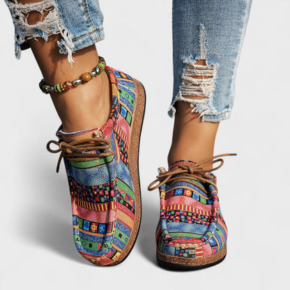 Bunte Damen-Sneaker mit Patchwork-Muster, getragen mit zerrissenen Jeans und Perlenarmband. Modische Freizeitschuhe, ideal für trendige Outfits.