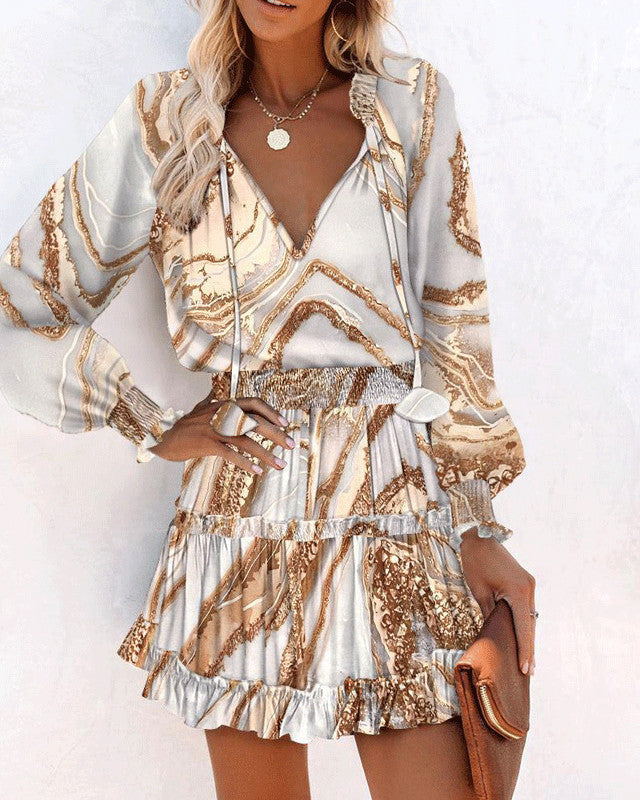 Frau in modischem, gemustertem Kleid mit langen Ärmeln und Rüschenrock, hält braune Clutch. Elegantes Outfit, ideal für Sommermode.