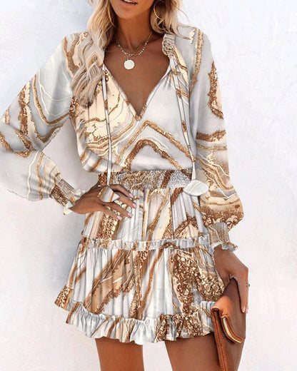 Frau in modischem, gemustertem Kleid mit langen Ärmeln und Rüschenrock, hält braune Clutch. Elegantes Outfit, ideal für Sommermode.