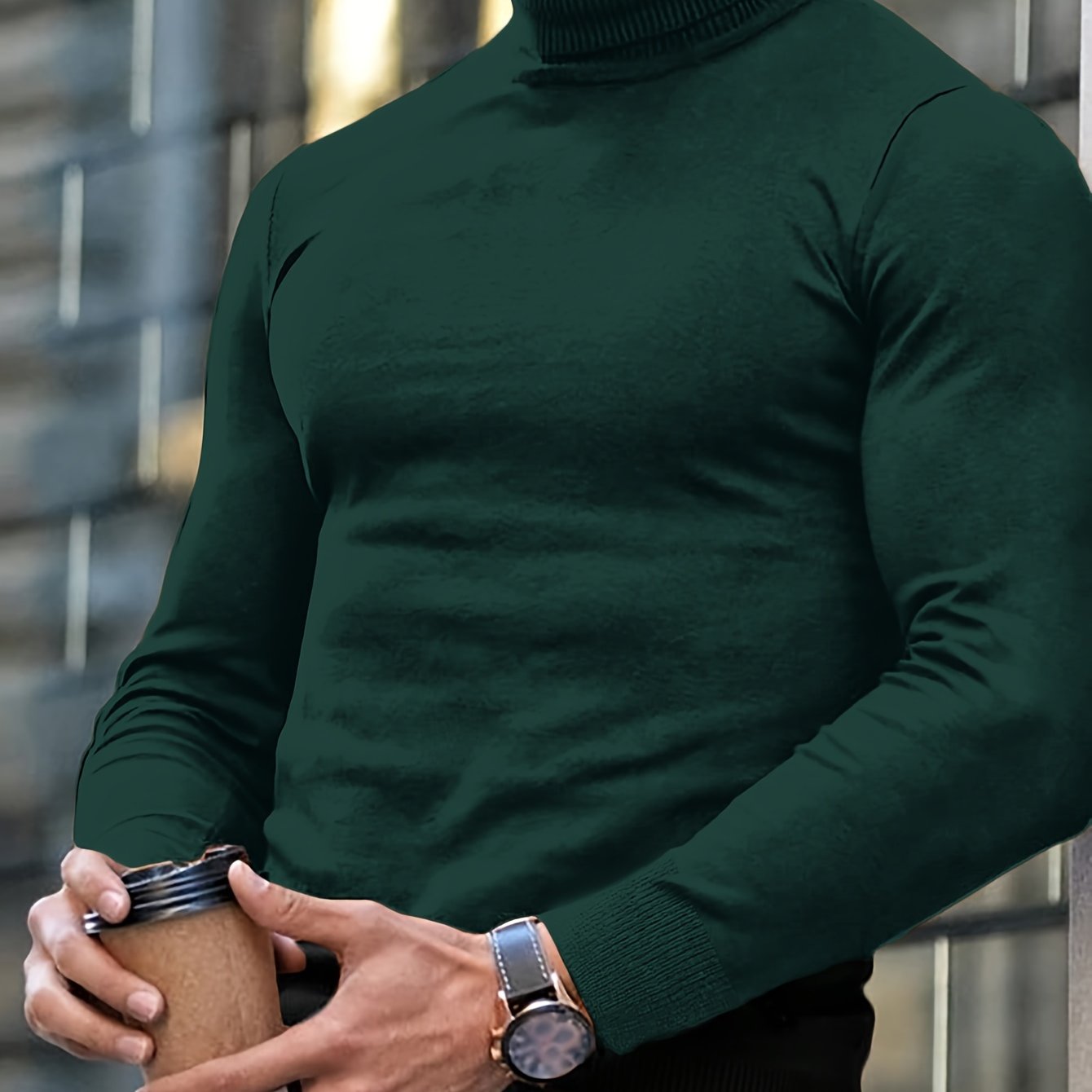 Mann in dunkelgrünem Rollkragenpullover hält Kaffeebecher, trägt Armbanduhr. Mode, Herrenbekleidung, urbaner Stil, Herbstmode.
