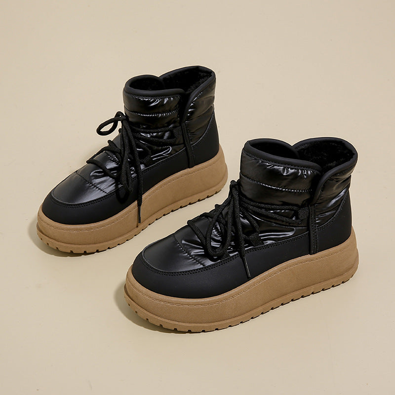 Schwarze Winterstiefel mit dicker Sohle und Schnürung auf beigem Hintergrund. Modische, warme Damenstiefel für kalte Tage.