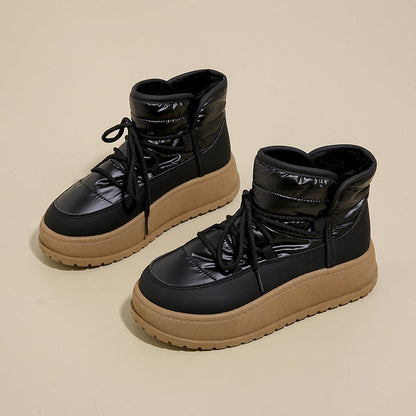 Schwarze Winterstiefel mit dicker Sohle und Schnürung auf beigem Hintergrund. Modische, warme Damenstiefel für kalte Tage.