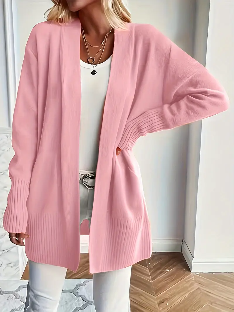 Frau in rosa Strickjacke, weißem Top und Hose. Modische Damenbekleidung, lässiger Look, eleganter Stil, gemütlicher Cardigan für Herbstmode.