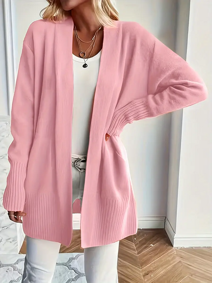 Frau in rosa Strickjacke, weißem Top und Hose. Modische Damenbekleidung, lässiger Look, eleganter Stil, gemütlicher Cardigan für Herbstmode.