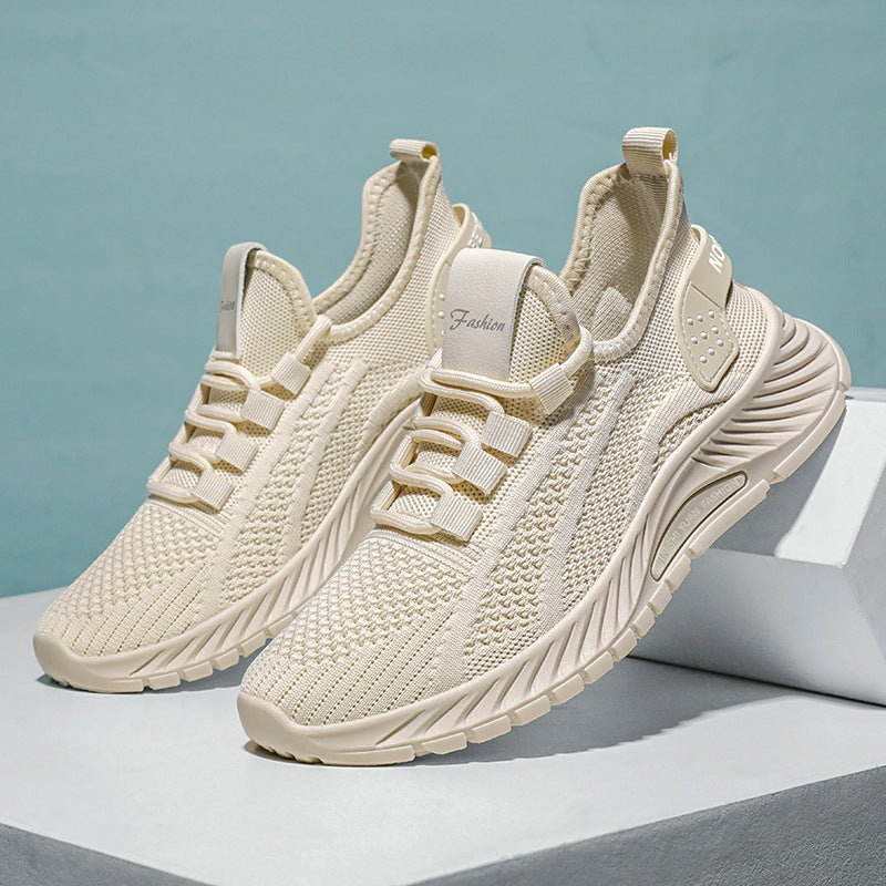 Beige Sportschuhe mit atmungsaktivem Strick-Obermaterial, modischem Design und rutschfester Sohle auf weißem Podest vor blauem Hintergrund.
