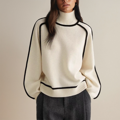 Frau trägt cremefarbenen Rollkragenpullover mit schwarzen Akzenten und grauer Hose. Modetrend, eleganter Winterlook, Damenmode.