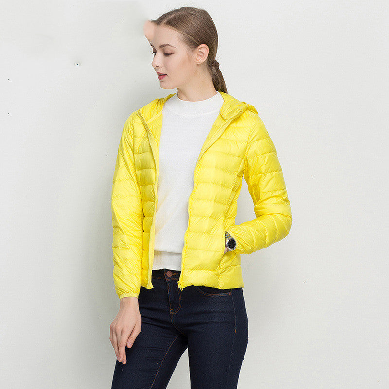 Frau in gelber Daunenjacke, weißem Pullover und blauer Jeans. Modetrend, Damenbekleidung, Herbstmode, Outdoorjacke, stilvoll und modern.
