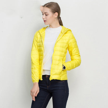 Frau in gelber Daunenjacke, weißem Pullover und blauer Jeans. Modetrend, Damenbekleidung, Herbstmode, Outdoorjacke, stilvoll und modern.