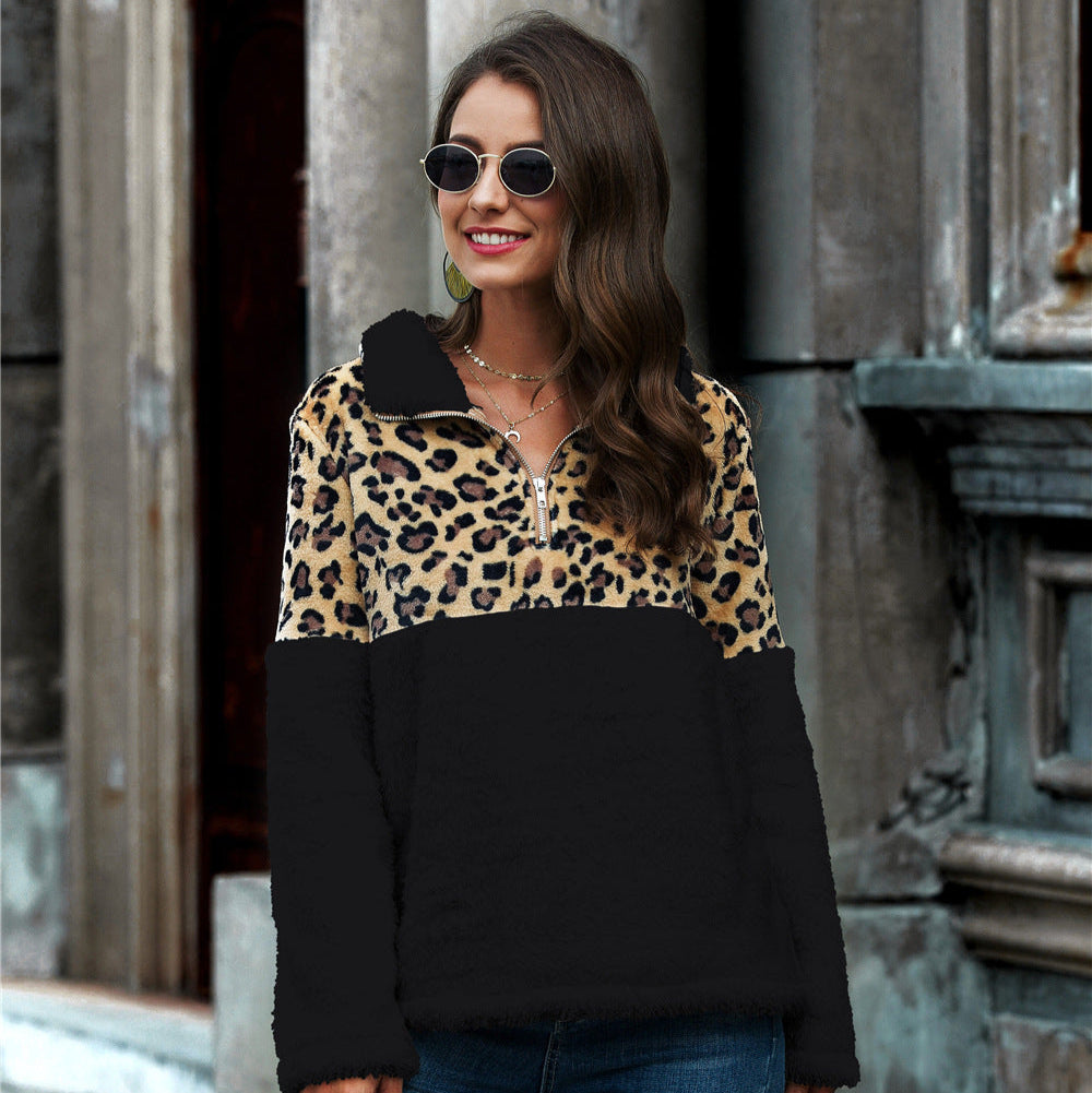 Frau mit Sonnenbrille trägt Leopardenmuster-Pullover und Jeans, steht vor urbaner Kulisse. Modetrend, Streetstyle, Herbstmode.