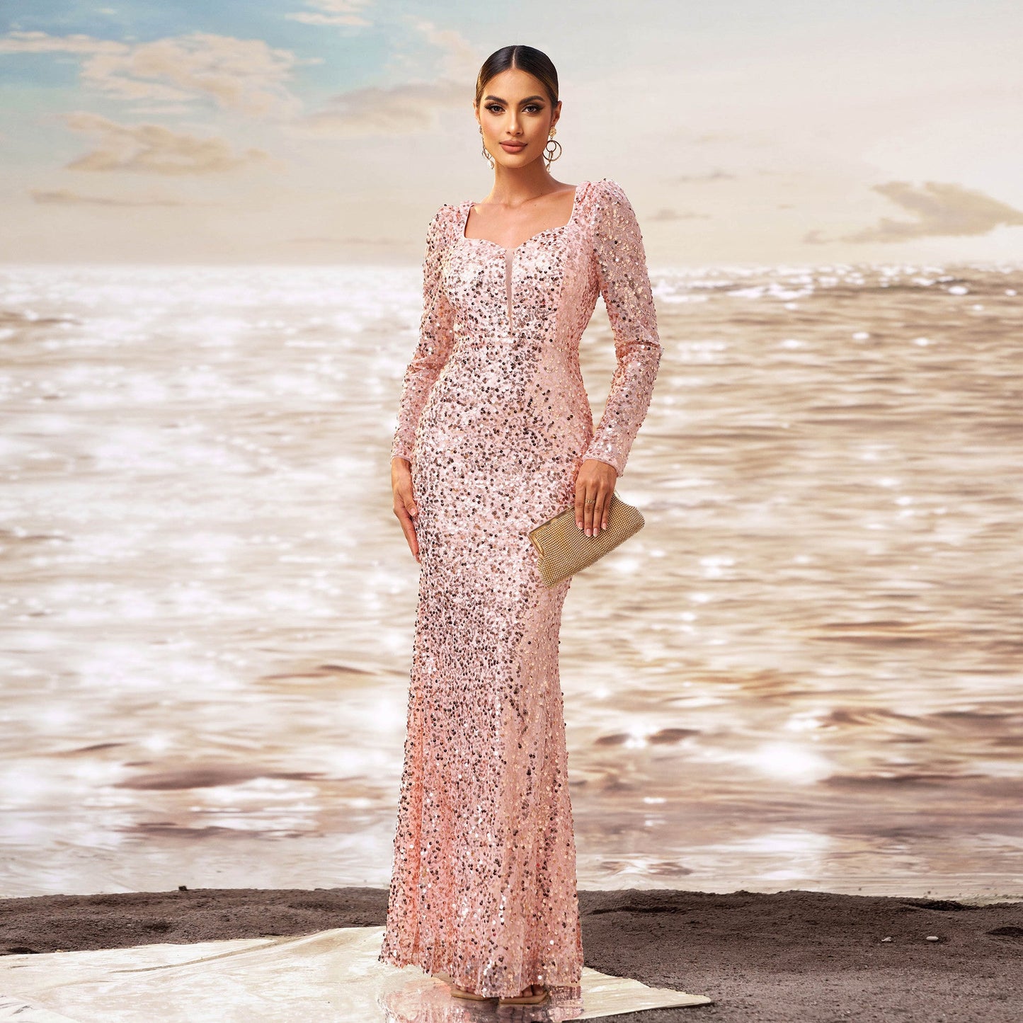 Elegante Frau in glitzerndem, rosa Abendkleid am Strand, hält goldene Clutch. Sonnenuntergang am Meer im Hintergrund. Glamouröse Modefotografie.
