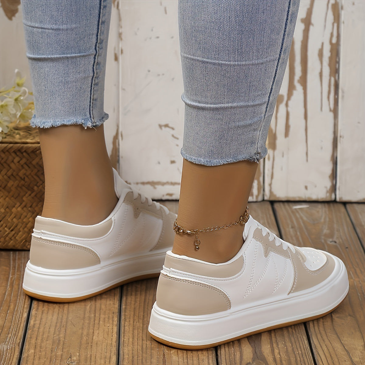 Damen Sneaker in Weiß und Beige, getragen mit hellblauen Jeans. Modische Freizeitschuhe auf Holzboden, ideal für lässige Outfits.