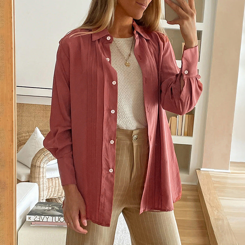 Frau in rosa Bluse und beiger Hose, steht in modernem Wohnzimmer, hält Smartphone. Stilvolle Mode, Freizeitkleidung, Innenarchitektur.