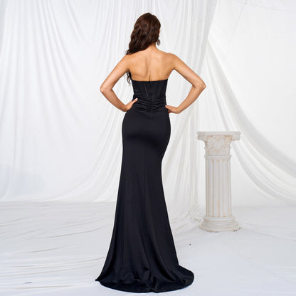 Frau in elegantem, schwarzem Abendkleid vor weißem Hintergrund mit Säule, Rückenansicht. Perfekt für Gala, Ball oder formelle Anlässe.