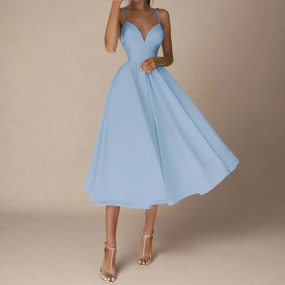 Frau in elegantem, hellblauem Abendkleid mit Spaghettiträgern und ausgestelltem Rock, trägt silberne High Heels. Perfekt für formelle Anlässe.