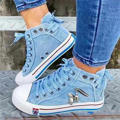 Blaue High-Top-Sneaker aus Denim mit Reißverschluss und Anhängern, getragen von Person in Jeans. Modische Freizeitschuhe, urbaner Stil.
