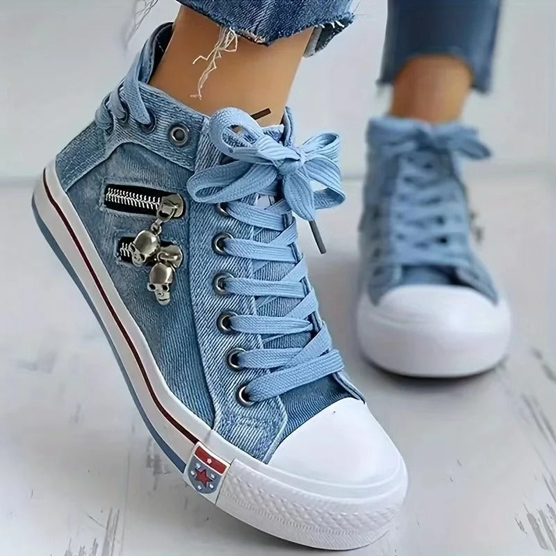 Blaue Jeans-Sneaker mit weißen Gummisohlen, Zierreißverschluss und Totenkopfanhänger. Modische Damen-Schuhe, ideal für Freizeit und Streetwear.