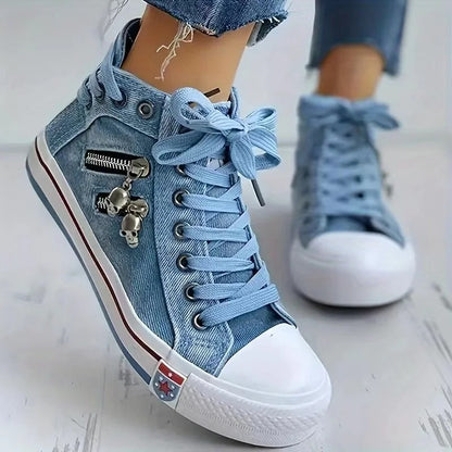 Blaue Jeans-Sneaker mit weißen Gummisohlen, Zierreißverschluss und Totenkopfanhänger. Modische Damen-Schuhe, ideal für Freizeit und Streetwear.