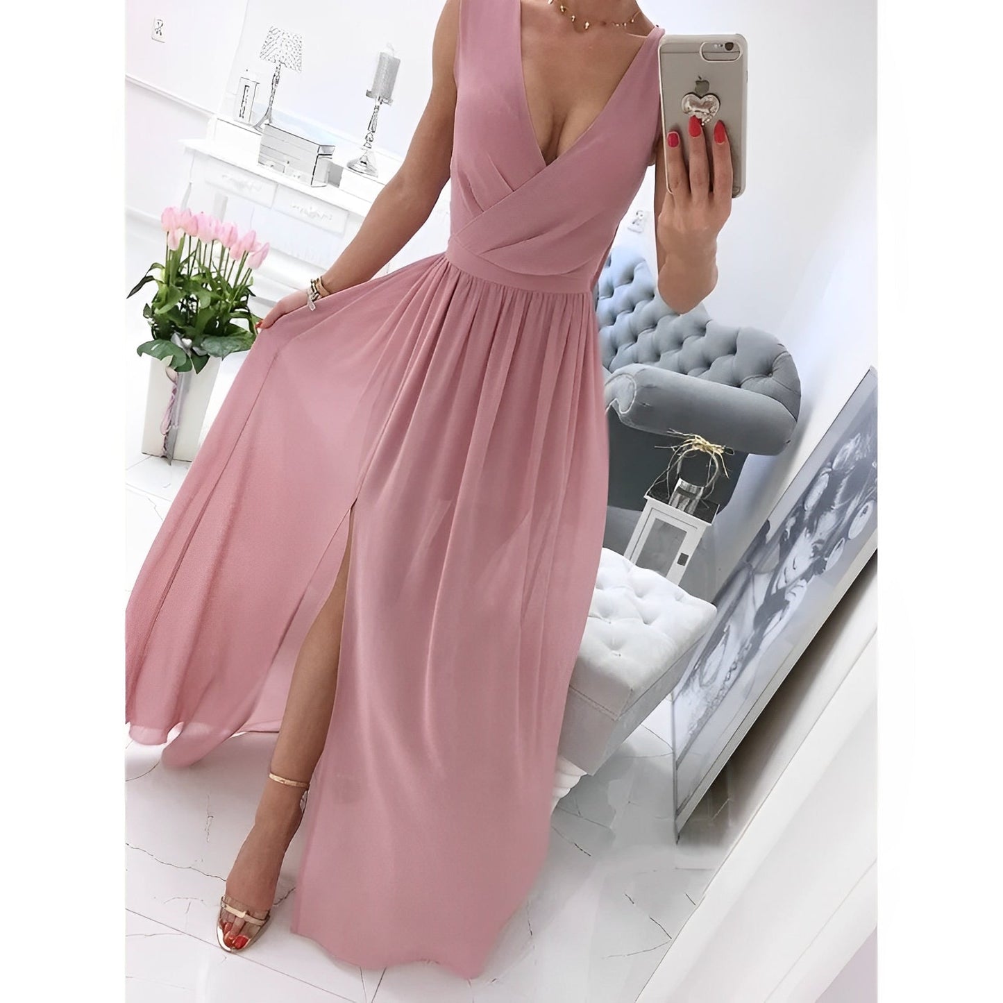 Elegantes rosa Abendkleid mit V-Ausschnitt und Beinschlitz, getragen von Frau im modernen Wohnzimmer. Perfekt für formelle Anlässe und Hochzeiten.