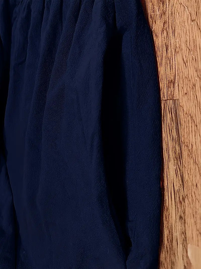 Dunkelblaues, strukturiertes Kleidungsstück aus Stoff, hängt an einer Holzwand. Mode, Textil, Kleidung, Stoffstruktur, Innenraum.