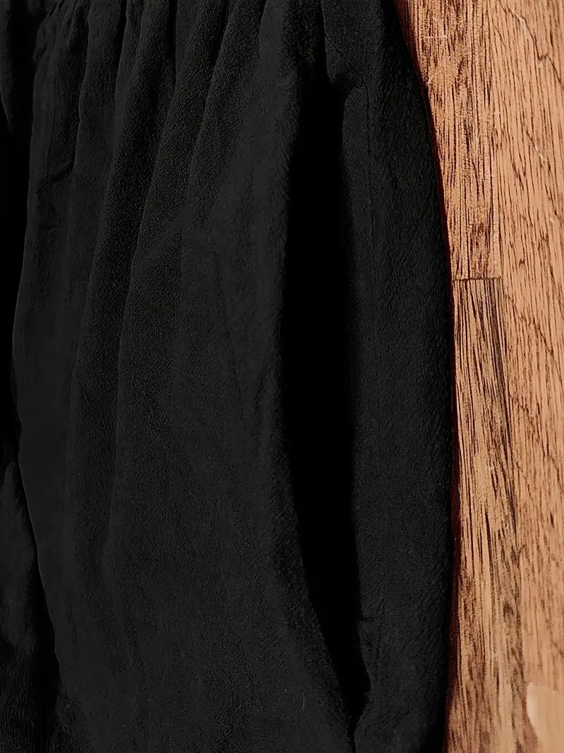 Schwarze, weiche Jogginghose aus Fleece auf Holzboden. Bequeme Sportbekleidung, ideal für Freizeit und Fitness. Trendige, warme Jogginghose.