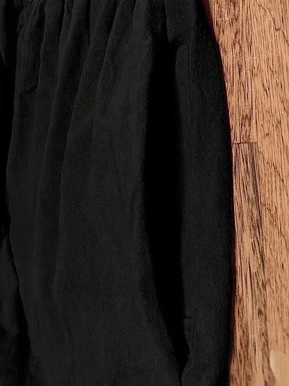 Schwarze, weiche Jogginghose aus Fleece auf Holzboden. Bequeme Sportbekleidung, ideal für Freizeit und Fitness. Trendige, warme Jogginghose.