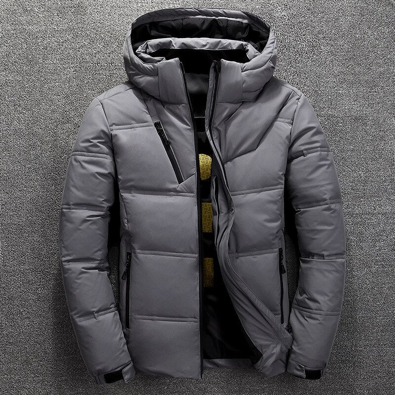 Graue Winterjacke mit Kapuze, Reißverschlusstaschen und gestepptem Design auf grauem Hintergrund. Herrenmode, warme Outdoor-Bekleidung.