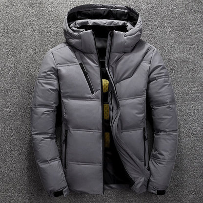 Graue Winterjacke mit Kapuze, Reißverschlusstaschen und gestepptem Design auf grauem Hintergrund. Herrenmode, warme Outdoor-Bekleidung.
