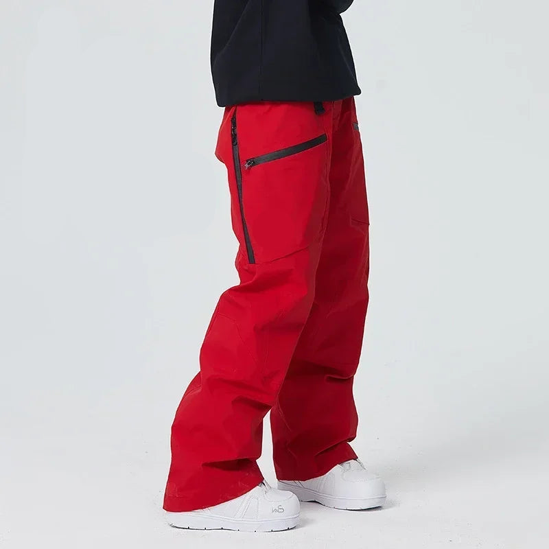 Rote Skihose mit schwarzen Reißverschlüssen, getragen von Person in schwarzem Oberteil und weißen Schuhen. Ideal für Wintersport und Outdoor-Aktivitäten.