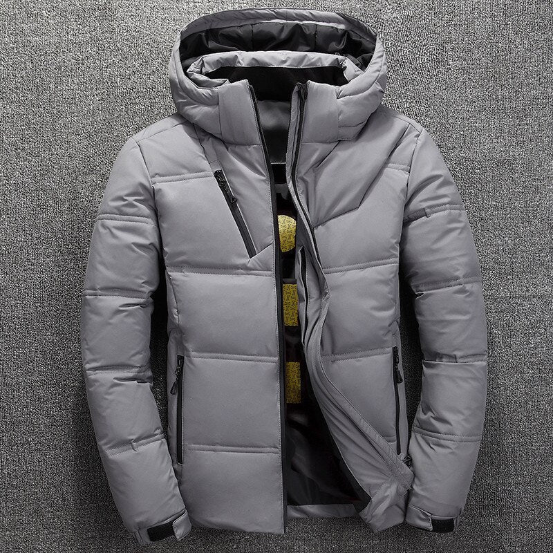 Graue Winterjacke mit Kapuze, Reißverschlusstaschen und gestepptem Design auf grauem Hintergrund. Herrenmode, warme Outdoor-Bekleidung.