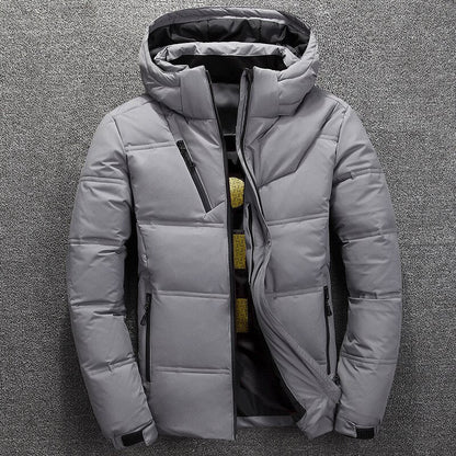 Graue Winterjacke mit Kapuze, Reißverschlusstaschen und gestepptem Design auf grauem Hintergrund. Herrenmode, warme Outdoor-Bekleidung.