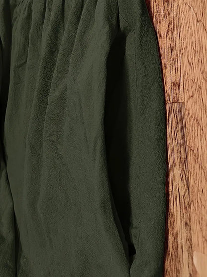 Grünes Langarmshirt aus Baumwolle auf Holzboden, knitterfrei. Ideal für Herbstmode, nachhaltige Kleidung, stilvolle Freizeitkleidung.