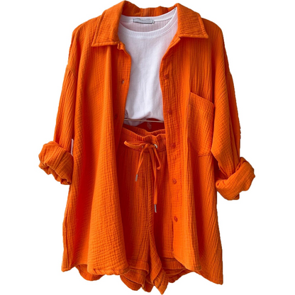 Orangefarbener Damen-Zweiteiler aus Baumwolle, bestehend aus Hemd und Shorts, kombiniert mit weißem T-Shirt. Modetrend, Sommeroutfit, Freizeitkleidung.
