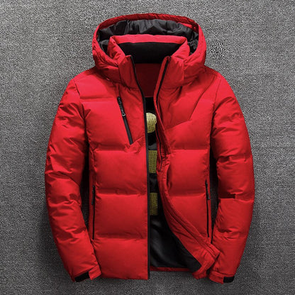 Rote Daunenjacke mit Kapuze, Reißverschluss und Taschen auf grauem Hintergrund. Wintermode, warme Outdoor-Bekleidung, Herrenjacke.