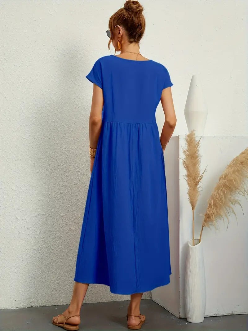 Frau in blauem Maxikleid, Rückansicht, steht neben weißer Vase mit Pampasgras, Sommermode, lässiger Stil, minimalistisches Design.
