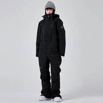 Person in schwarzer Winterjacke und Hose, graue Mütze, weiße Schuhe, vor grauem Hintergrund. Wintermode, Outdoor-Bekleidung, Skibekleidung.