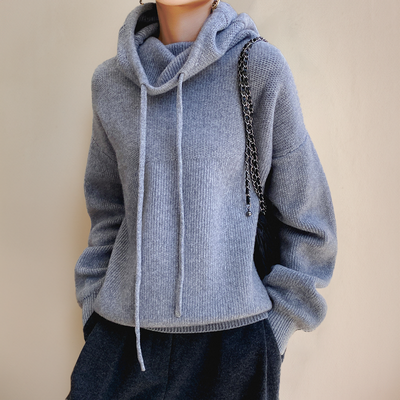 Grauer Strickpullover mit Kapuze und Kordelzug, getragen von einer Person. Modischer, bequemer Hoodie für Herbst- und Wintermode.