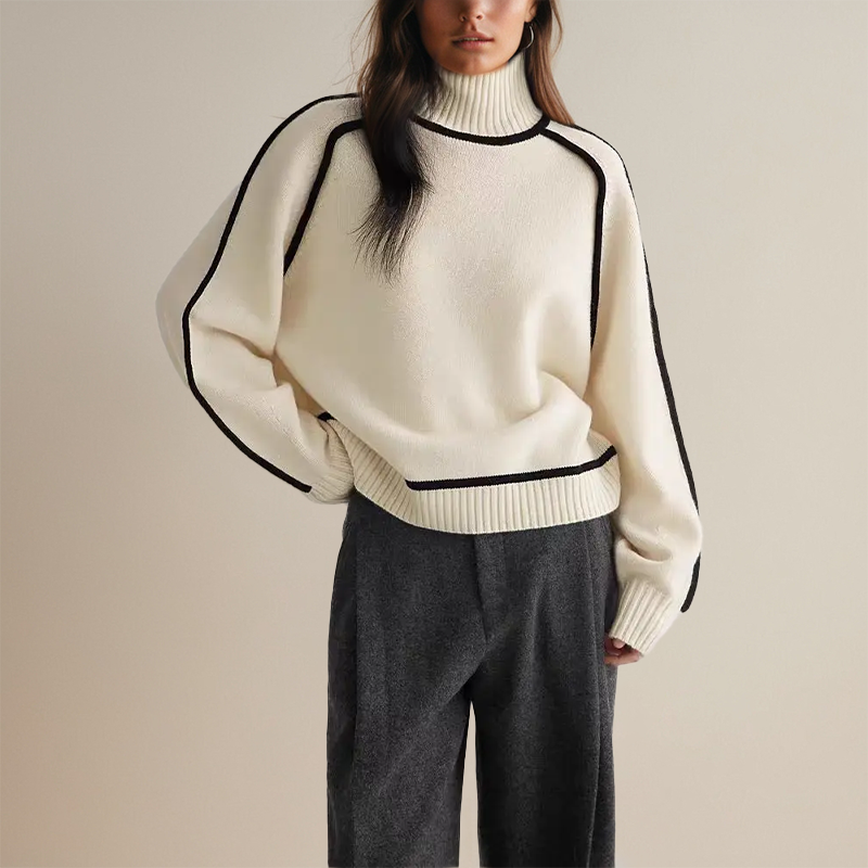 Frau in cremefarbenem Rollkragenpullover mit schwarzen Akzenten und grauer Hose. Modetrend, Herbstmode, eleganter Look, Damenbekleidung.