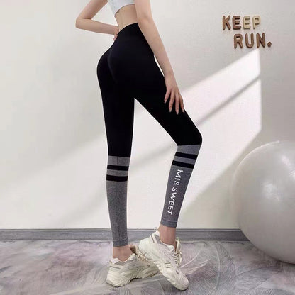 Frau in schwarzer Leggings mit grauen Streifen, Sport-BH, steht neben Gymnastikball, Fitnessstudio, "Keep Run" Wanddeko, Sportbekleidung.
