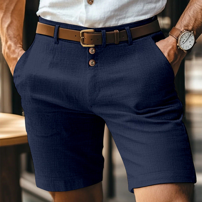 Mann in eleganter, dunkelblauer Chino-Shorts mit braunem Ledergürtel und weißem Hemd. Sommermode, Herrenbekleidung, stilvolle Freizeitkleidung.