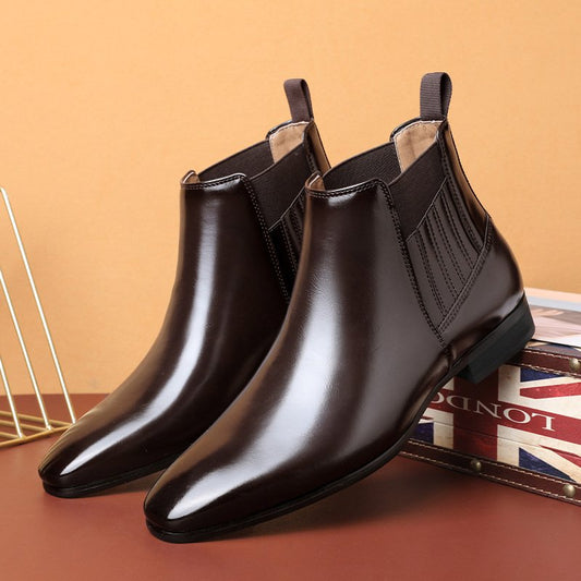 Elegante braune Chelsea Boots aus Leder, glänzend poliert, auf einem Tisch mit britischer Flagge im Hintergrund. Ideal für Herrenmode und Business-Look.
