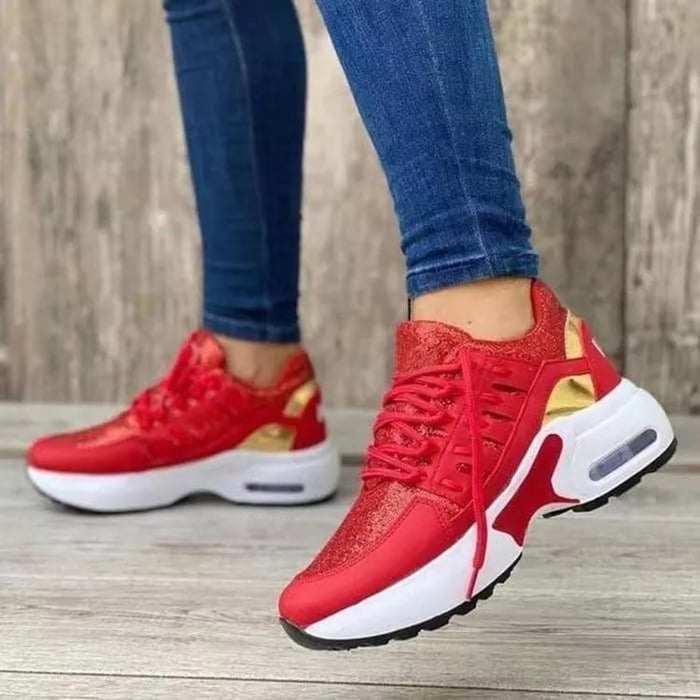 Rote Damen-Sneaker mit goldenen Akzenten, weiße Sohle, getragen von Person in blauen Jeans. Modische Sportschuhe, ideal für Freizeit und Sport.