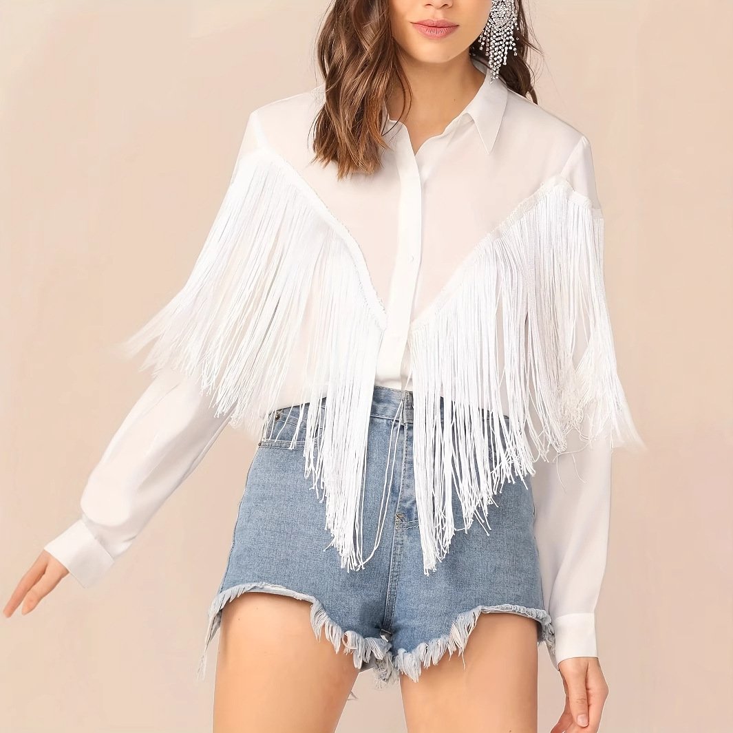 Frau trägt weiße Fransenbluse und zerrissene Jeansshorts. Modetrend, lässiger Sommerlook, stilvolle Damenbekleidung, Fransen-Details.