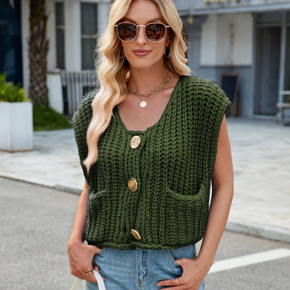 Frau mit blonder Welle, Sonnenbrille, grünem Strickweste mit großen Knöpfen, blauer Jeans, steht draußen. Modetrend, lässiger Stil, Sommermode.
