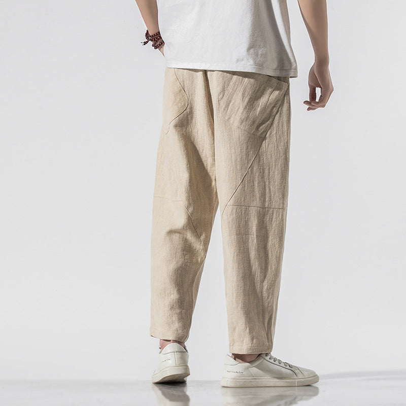 Person in beigen Leinenhosen und weißen Sneakers, Rückansicht. Modetrend, lässiger Stil, Herrenbekleidung, minimalistisch, komfortabel.