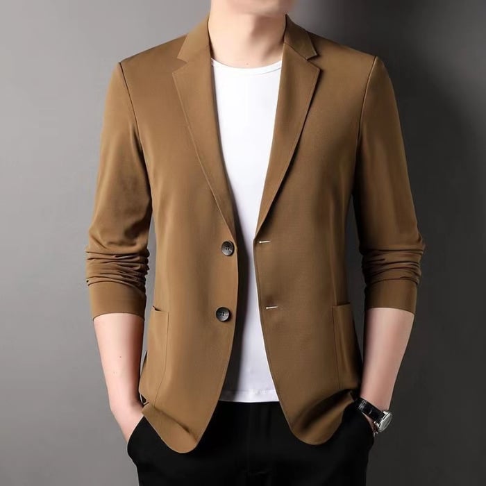 Mann in braunem Blazer und weißem T-Shirt, Hände in den Taschen. Stilvolle Herrenmode, eleganter Look, Freizeitkleidung, Mode für Männer.