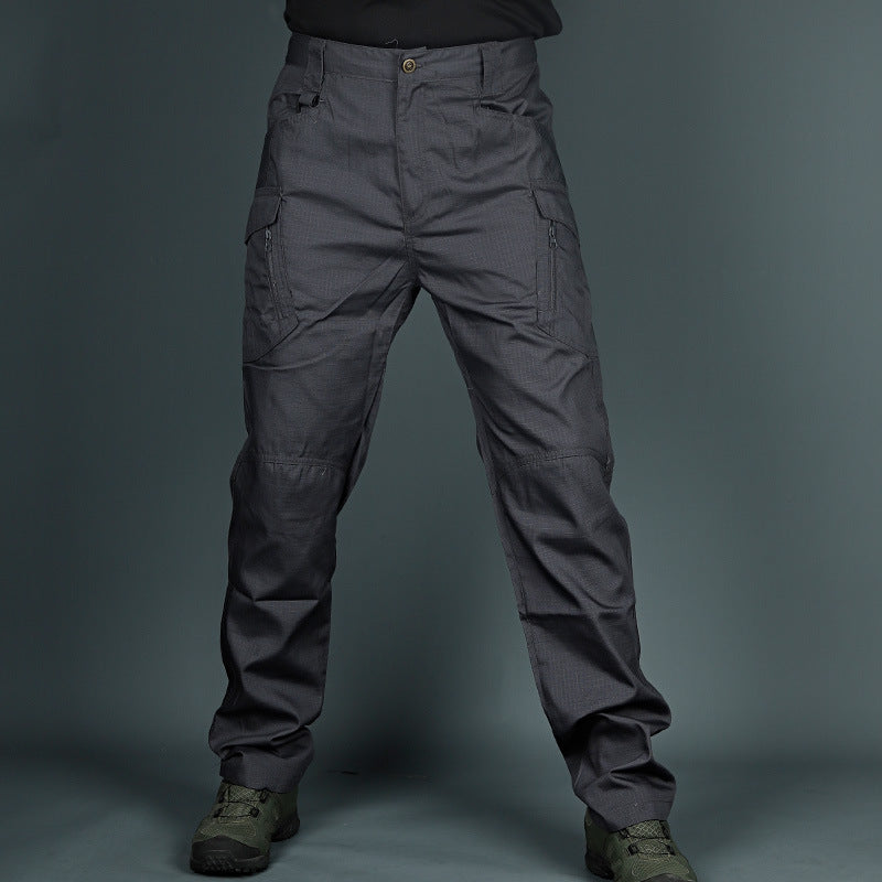 Graue taktische Hose mit mehreren Taschen, robustem Material und militärischem Design, getragen mit olivgrünen Stiefeln vor grauem Hintergrund.
